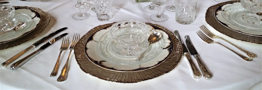 Cut crystal vintage glasses and champagne saucers, Vintage glass sundae dishes layered up on navy and white vintage plate. complete with silver vintage cutlery