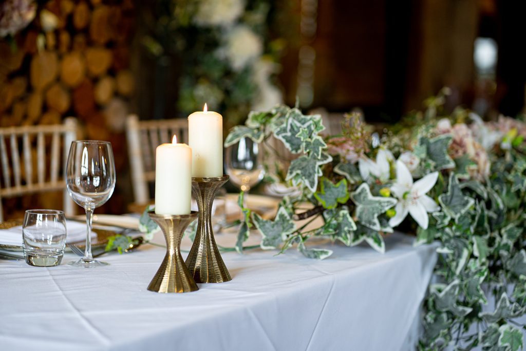 Hourglass shaped gold candlesticks at two heights for pillar candles which are lit for hire