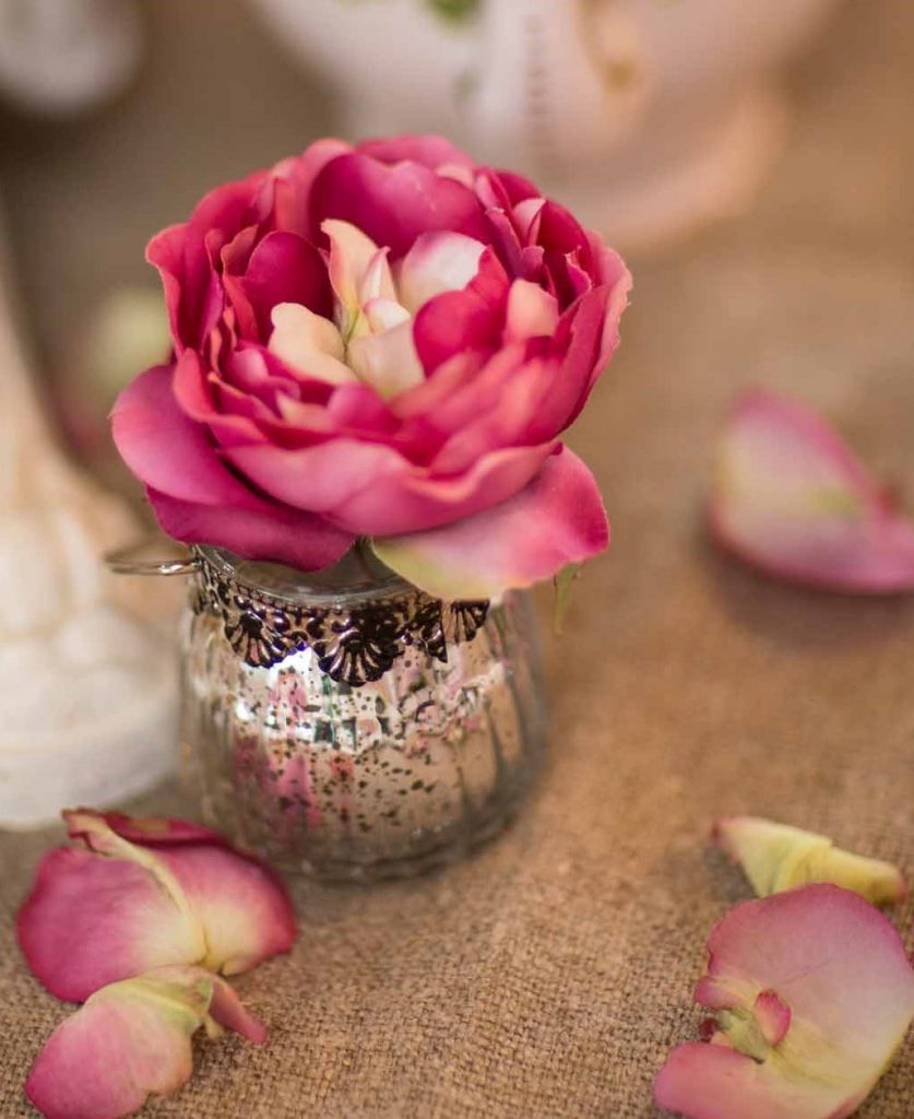 small silver foil glass tealight holder with an ornate detail around the top and a pink rose using in it as a posy vase for hire