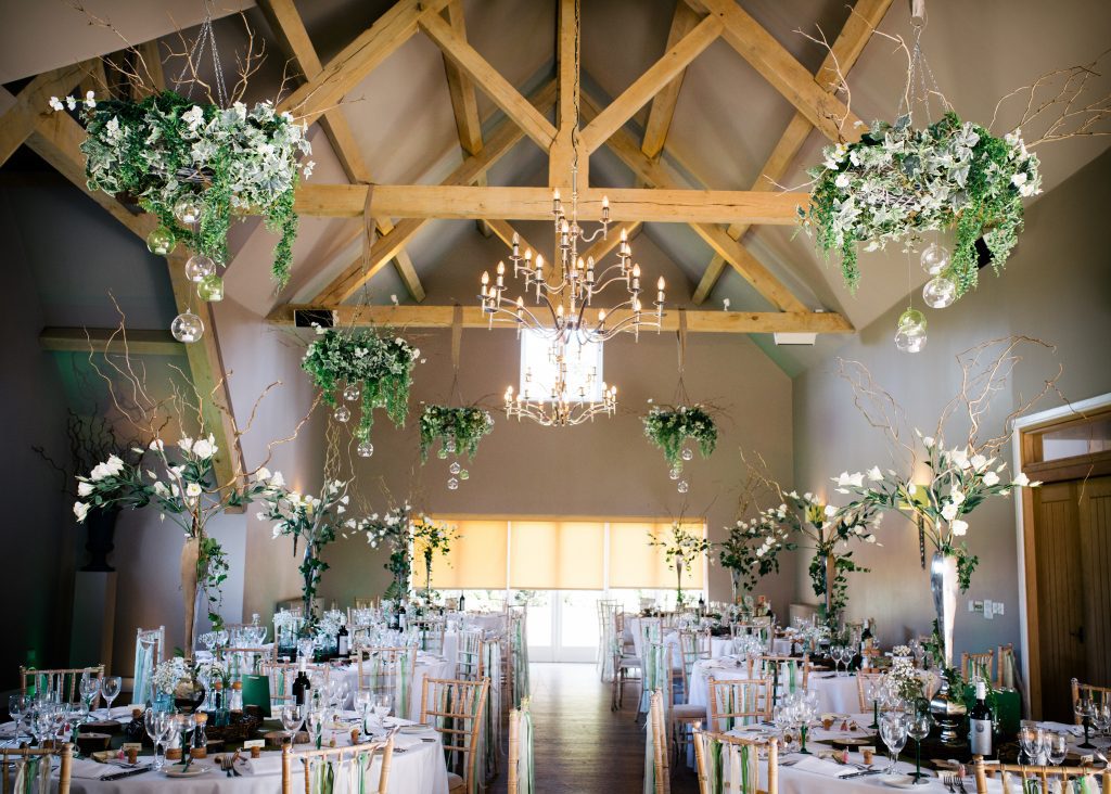 aerial view of woodland wedding and event decor ideas of hanging wreaths with ivy and foliage and glass baubles, table centres of silver vases with gold twigs, white roses and lisianthus available to Hire, pictured at Hyde Barn